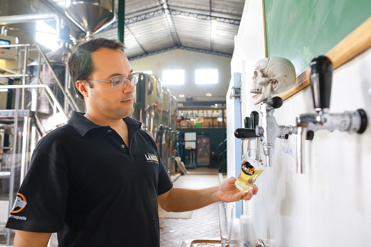 Samuel Mendonça de Faria enche copo com cerveja fabricada pela Landel em Barão